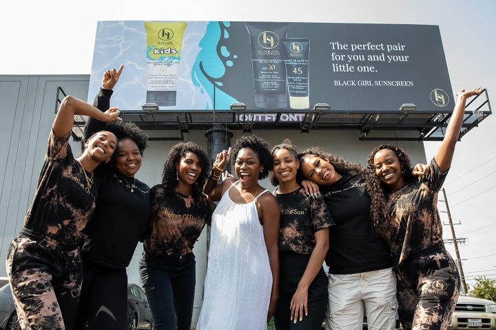 mois d'affaires noir - équipe de protection solaire fille noire devant un panneau d'affichage promotionnel